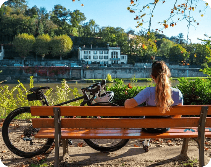 Femme cycliste posé sur un banc et qui regarde la vue